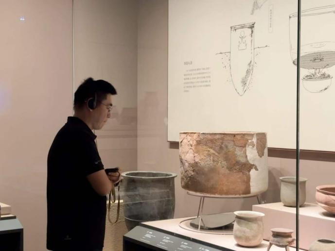 观众在山东博物馆陶器展柜前收听导览