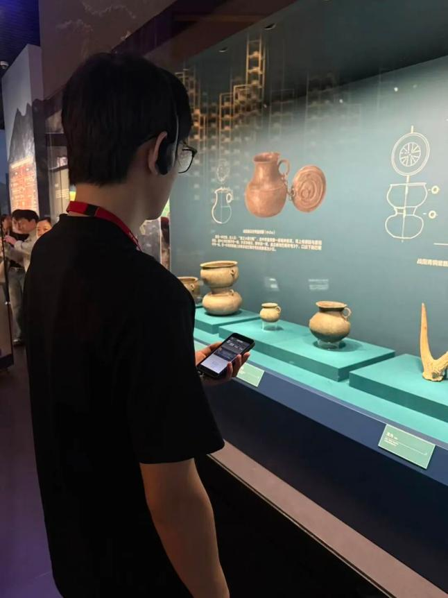 观众在三峡博物馆陶器展柜前使用导览机